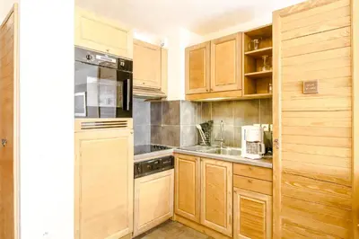 a small kitchen with wooden cabinets and a sink at Large one-bedroom apartment, wheelchair adapted, Les Terrasses d'Eos in Flaine