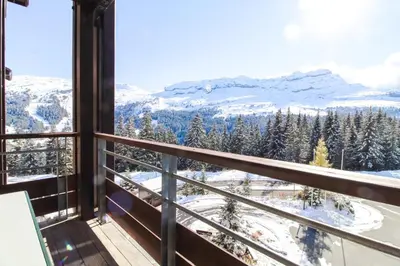 a table and chairs on a balcony with a view of the mountains at Stunning 3-bedroom apartment with mountain views in Flaine
