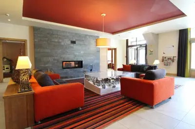 a living room with orange chairs and a fireplace at Stunning 3-bedroom apartment with mountain views in Flaine