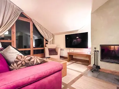 a living room with a pink couch and a tv at Beautiful one-bedroom apartment with fireplace and stunning views in Flaine