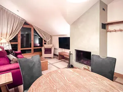 a living room with a table and a couch at Beautiful one-bedroom apartment with fireplace and stunning views in Flaine