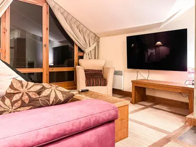 a living room with a couch and a tv at Beautiful one-bedroom apartment with fireplace and stunning views in Flaine