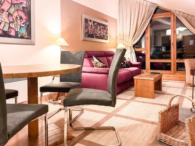 a living room with a purple couch and a table at Beautiful one-bedroom apartment with fireplace and stunning views in Flaine