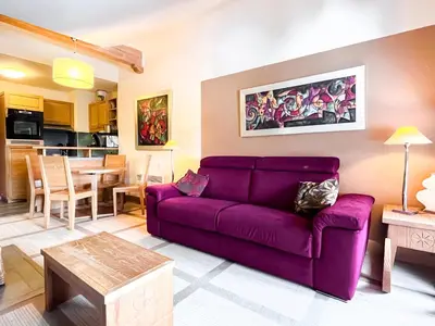 a living room with a purple couch and a table at Beautiful one-bedroom apartment with fireplace and stunning views in Flaine