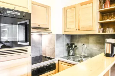 a kitchen with wooden cabinets and a stove top oven at Beautiful one-bedroom apartment with fireplace and stunning views in Flaine