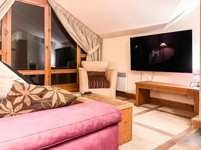 a living room with a couch and a tv at Beautiful one-bedroom apartment with fireplace and stunning views in Flaine