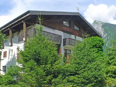 a building with trees in front of a mountain at T2 calme à Samoëns - 4 pers, animaux admis - FR-1-629-70 in Samoëns