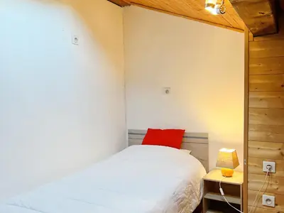 a small bedroom with a bed and a red pillow at Chalet au centre de Samoëns avec jardin et cheminée - FR-1-624-17 in Samoëns