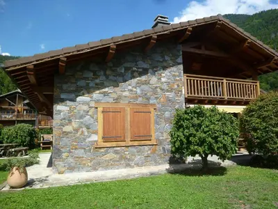 a stone house with a wooden door and a balcony at Chalet au centre de Samoëns avec jardin et cheminée - FR-1-624-17 in Samoëns