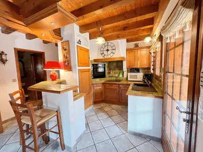 a kitchen with wooden cabinets and a counter top at Chalet au centre de Samoëns avec jardin et cheminée - FR-1-624-17 in Samoëns