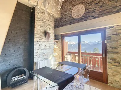 a room with a table and a balcony with mountains at 2 pièces + mezzanine au pied des pistes à Combloux - FR-1-560-73 in Combloux