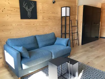 a living room with a blue couch and a ladder at Studio moderne avec balcon et parking dans Samoëns - FR-1-624-71 in Samoëns
