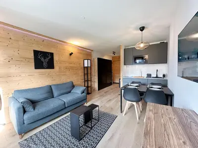a living room with a blue couch and a kitchen at Studio moderne avec balcon et parking dans Samoëns - FR-1-624-71 in Samoëns