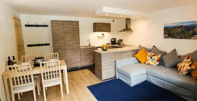 a living room with a couch and a table and a kitchen at Chalet Grand Balcon in Les Houches
