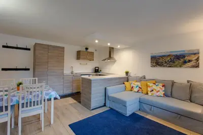 a living room with a couch and a kitchen at Chalet Grand Balcon in Les Houches