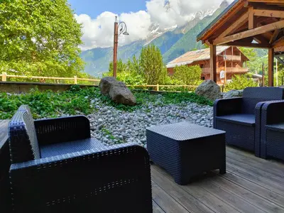 a patio with two chairs and a table and mountains at Chalet Grand Balcon in Les Houches
