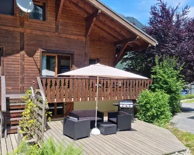 a wooden deck with a table and an umbrella at Chalet Tontine, 3 bedrooms, sauna, terrace and great views ! in Les Houches