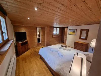 a bedroom with a large bed and a television at Chalet Tontine, 3 bedrooms, sauna, terrace and great views ! in Les Houches