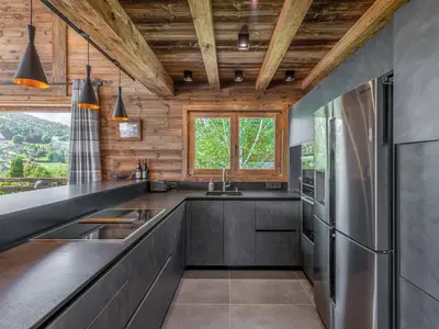a kitchen with stainless steel appliances and wooden ceilings at Chalet Luxe 12 Pers. Face aux Pistes avec Skiroom, Garage, Salle de Sport et Services Inclus - FR-1-569-19 in Demi-Quartier
