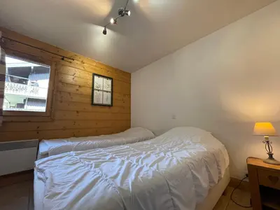 a bedroom with a large bed with white sheets at Appartement T3 au centre de Samoëns avec balcon, WIFI et parking - FR-1-624-23 in Samoëns