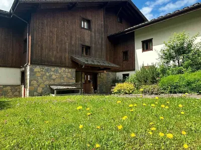 a large wooden building with a field of grass and flowers at Appartement duplex spacieux avec piscine et WiFi à Samoëns - FR-1-624-9 in Samoëns