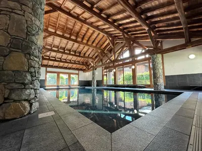 a swimming pool in a building with a stone wall at Appartement duplex spacieux avec piscine et WiFi à Samoëns - FR-1-624-9 in Samoëns
