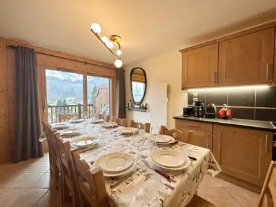 a dining room with a table with chairs and a kitchen at Appartement duplex spacieux avec piscine et WiFi à Samoëns - FR-1-624-9 in Samoëns