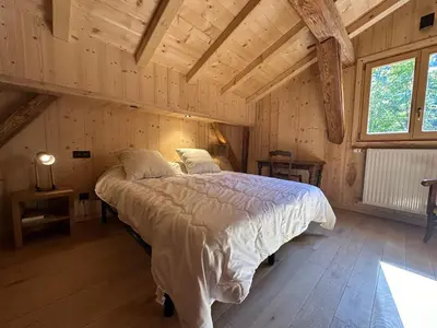 a bedroom with a large bed in a room with wooden ceilings at Chalet moderne à Samoëns avec cheminée et terrasse - FR-1-624-5 in Samoëns