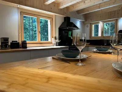 a kitchen with a wooden table with wine glasses at Chalet moderne à Samoëns avec cheminée et terrasse - FR-1-624-5 in Samoëns