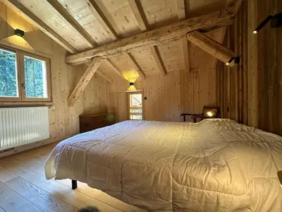 a bedroom with a bed in a room with wooden ceilings at Chalet moderne à Samoëns avec cheminée et terrasse - FR-1-624-5 in Samoëns