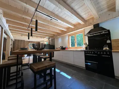 a kitchen with a black stove and a wooden ceiling at Chalet moderne à Samoëns avec cheminée et terrasse - FR-1-624-5 in Samoëns