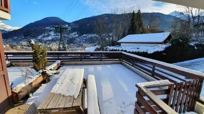 a snow covered deck with a bench on a balcony at Appartement l'Edel - Vue Massif Mont-Blanc in Saint-Gervais-les-Bains