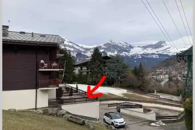 a red plane flying over a building with a car at Appartement l'Edel - Vue Massif Mont-Blanc in Saint-Gervais-les-Bains