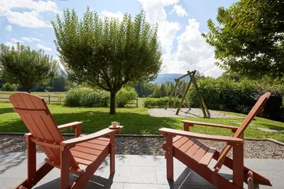 two wooden chairs sitting on a patio with a swing at Best Western Plus Pays du Mont Blanc in Sallanches