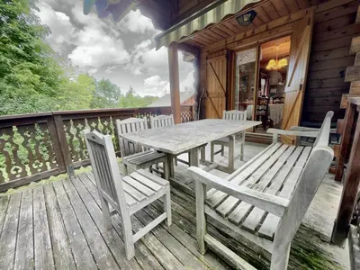 a wooden deck with a table and chairs on a cabin at Chalet 3 chambres calme, poêle à bois, proche piste et village, 6/8 pers, garage et parking - FR-1-572-243 in Les Carroz d'Araches