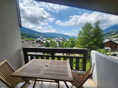 a wooden table and chairs on a balcony with a view at Charmant appartement 2 pièces mezzanine, animaux admis, Samoëns - FR-1-629-53 in Samoëns