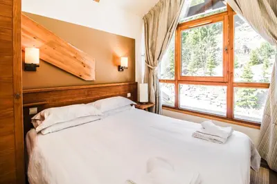 a bedroom with a white bed and a window at Two internally connecting 2-bed apartments with shared private entrance in Flaine