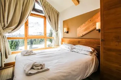 a bedroom with a white bed with a window at Two internally connecting 2-bed apartments with shared private entrance in Flaine