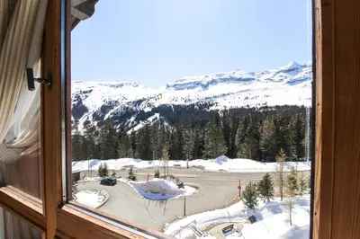 a window with a view of a snow covered mountain at Two internally connecting 2-bed apartments with shared private entrance in Flaine