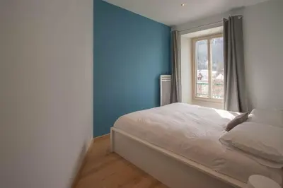 a bedroom with blue walls and a bed with a window at Les Aiguilles- Town centre luxury 2 bedroom apartment in Chamonix-Mont-Blanc