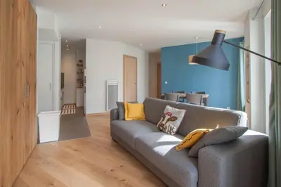 a living room with a gray couch and a blue wall at Les Aiguilles- Town centre luxury 2 bedroom apartment in Chamonix-Mont-Blanc