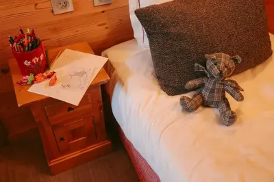 a teddy bear sitting on a bed next to a table at Les Grands Montets Hotel & Spa in Chamonix-Mont-Blanc