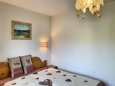 a bedroom with a bed and a chandelier at Joli 2 pièces + studio au centre de Combloux - FR-1-560-74 in Combloux