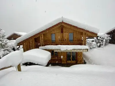 a log cabin in the snow next to a building at Chalet massif du Mont Blanc St Gervais Megeve in Saint-Gervais-les-Bains