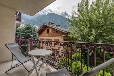 a balcony with a table and chairs and a mountain at Villa Vallet- Newly renovated 2 bedroom nestled just off the main street in Chamonix-Mont-Blanc