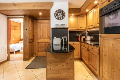 a kitchen with wooden cabinets and a clock on the wall at Villa Vallet- Newly renovated 2 bedroom nestled just off the main street in Chamonix-Mont-Blanc