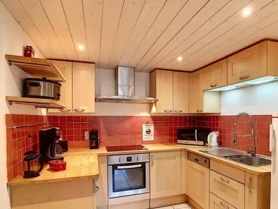 a kitchen with wooden cabinets and red tile on the wall at Ferme rénovée 4 ch, 3 sdb, PARKING, WIFI, proche pistes et commerces - FR-1-572-25 in Arâches-la-Frasse