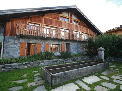 a large wooden house with a stone fountain in front of it at Ferme rénovée 12 pers, 450m des pistes, navette gratuite, balcon S-O, parking, WIFI - FR-1-572-23 in Arâches-la-Frasse