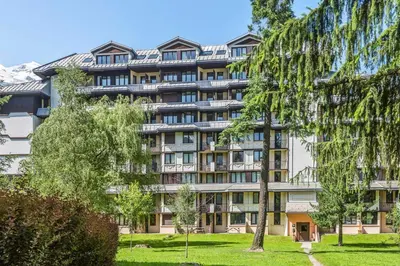a large apartment building with trees in front of it at Appartement Courmayeur - Welkeys in Chamonix-Mont-Blanc