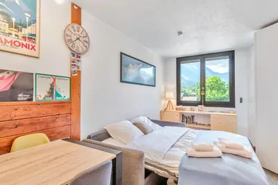 a bedroom with a bed and a table and a clock at Appartement Courmayeur - Welkeys in Chamonix-Mont-Blanc